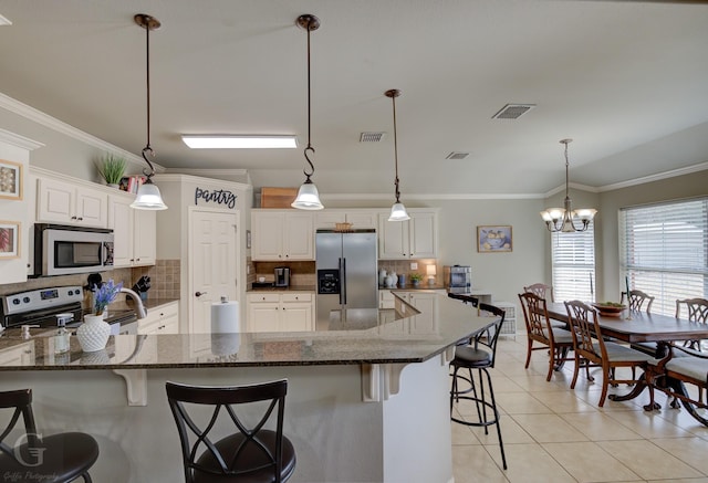 kitchen featuring stainless steel appliances, decorative light fixtures, a kitchen breakfast bar, and white cabinets