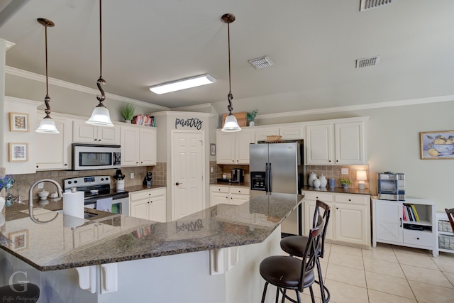 kitchen with decorative light fixtures, stainless steel appliances, dark stone counters, and white cabinets