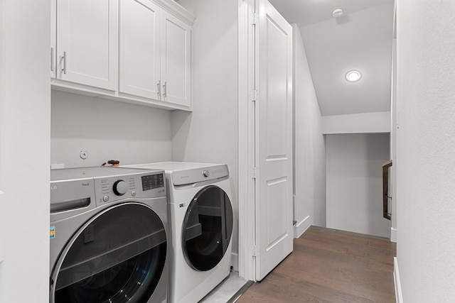 clothes washing area featuring dark wood-type flooring, cabinets, and washer and dryer