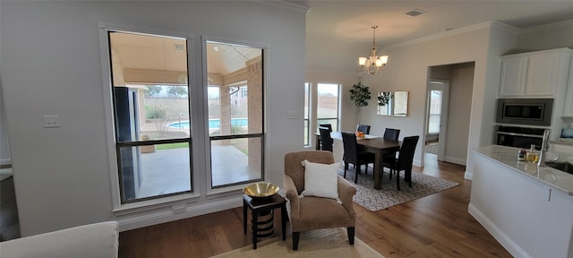 dining area featuring a notable chandelier, dark wood-type flooring, and ornamental molding