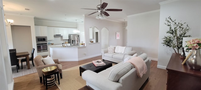 living room with crown molding, ceiling fan, sink, and light hardwood / wood-style floors