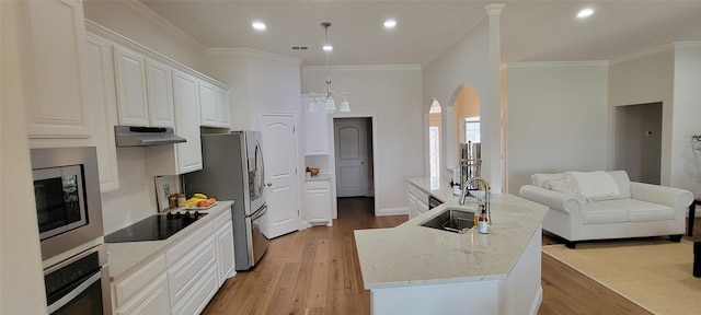 kitchen with sink, white cabinetry, light stone counters, appliances with stainless steel finishes, and a kitchen island with sink