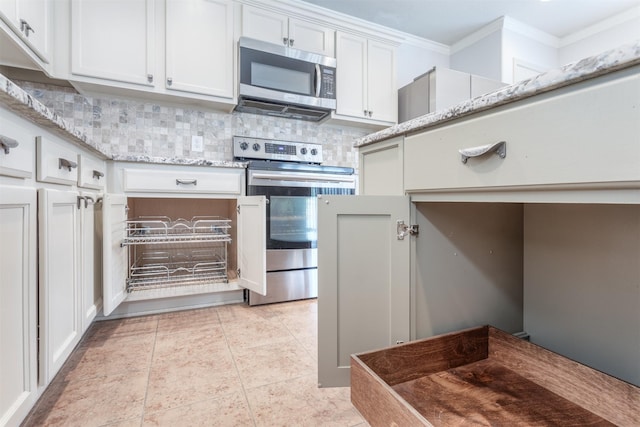 kitchen with white cabinets, decorative backsplash, light stone counters, stainless steel appliances, and crown molding