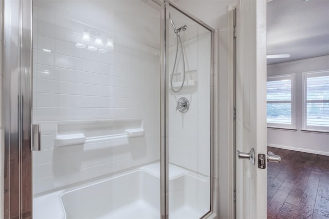 bathroom with a shower with door, wood-type flooring, and ornamental molding