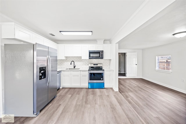 kitchen with sink, appliances with stainless steel finishes, white cabinetry, decorative backsplash, and light wood-type flooring