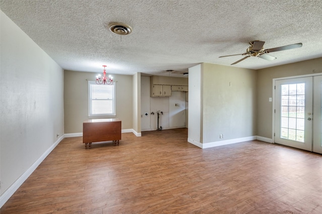 unfurnished room with ceiling fan with notable chandelier, light hardwood / wood-style flooring, and a textured ceiling