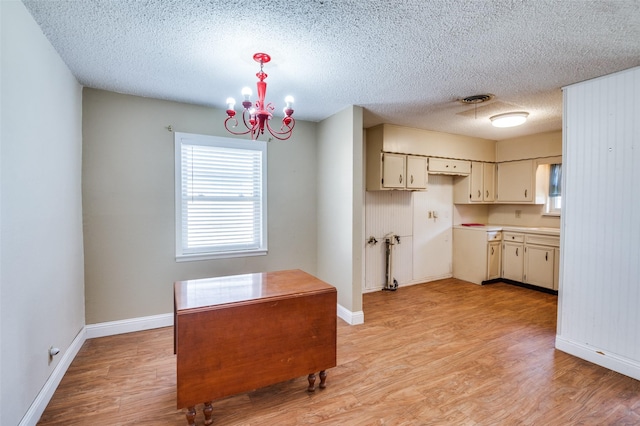 kitchen with a notable chandelier, light hardwood / wood-style floors, cream cabinetry, and a textured ceiling