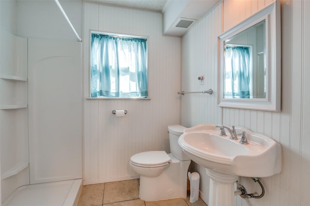 bathroom featuring tile patterned flooring, a shower, and toilet