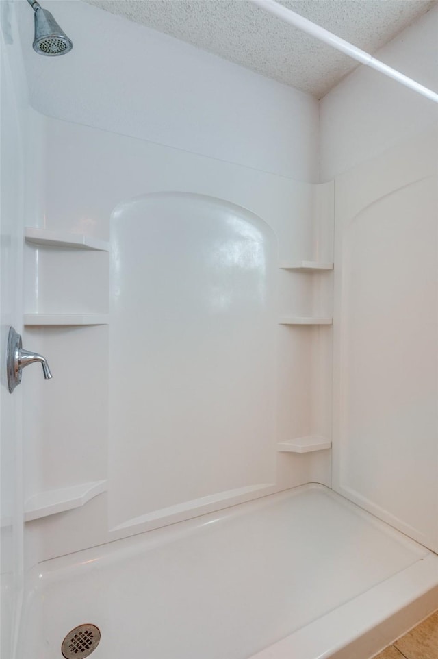 bathroom with a shower and a textured ceiling