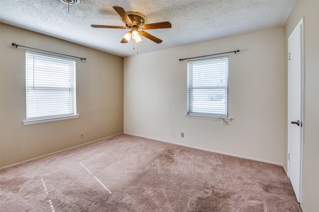 empty room featuring ceiling fan, light colored carpet, and a textured ceiling