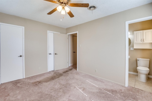 unfurnished bedroom featuring multiple closets, connected bathroom, light carpet, and a textured ceiling