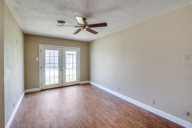 empty room featuring ceiling fan, light hardwood / wood-style flooring, a textured ceiling, and french doors