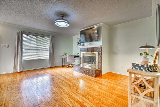 unfurnished living room with a tiled fireplace, crown molding, a textured ceiling, and light hardwood / wood-style flooring