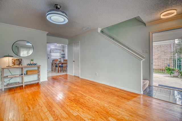 unfurnished living room featuring wood-type flooring, ornamental molding, and a textured ceiling