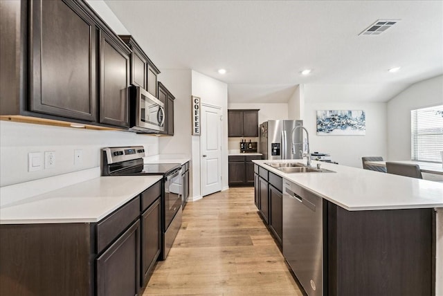 kitchen featuring visible vents, dark brown cabinets, a sink, light wood finished floors, and stainless steel appliances