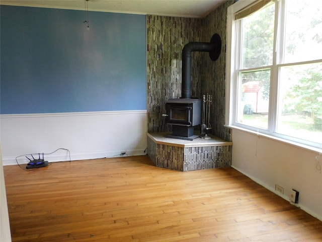 unfurnished living room featuring light hardwood / wood-style floors, a healthy amount of sunlight, and a wood stove