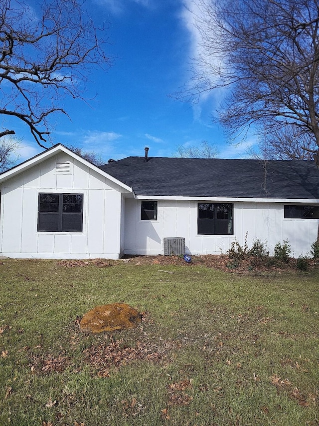 rear view of property with central AC and a lawn