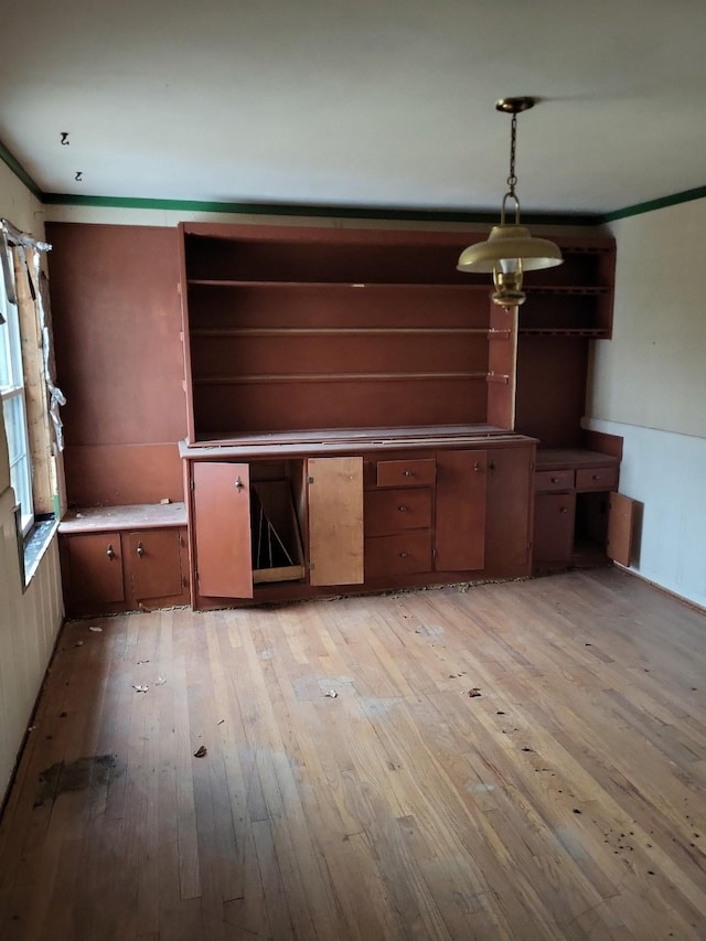 kitchen with ornamental molding, decorative light fixtures, and light hardwood / wood-style flooring