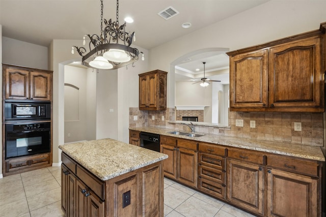 kitchen with sink, light stone counters, a center island, ceiling fan, and black appliances