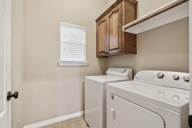 laundry area with cabinets, light tile patterned floors, and washer and clothes dryer