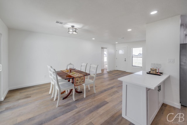 interior space with white cabinetry, kitchen peninsula, refrigerator, and light hardwood / wood-style flooring