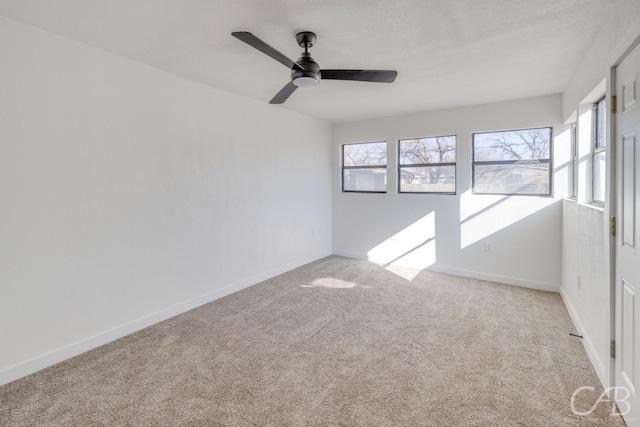 carpeted spare room featuring ceiling fan and a healthy amount of sunlight