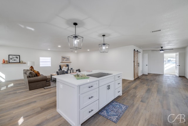 kitchen with white cabinetry, a center island, hanging light fixtures, plenty of natural light, and a barn door