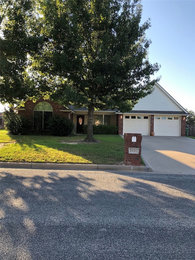 ranch-style house featuring concrete driveway, brick siding, a front lawn, and an attached garage