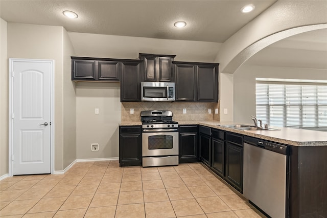 kitchen with tasteful backsplash, sink, light tile patterned floors, and appliances with stainless steel finishes