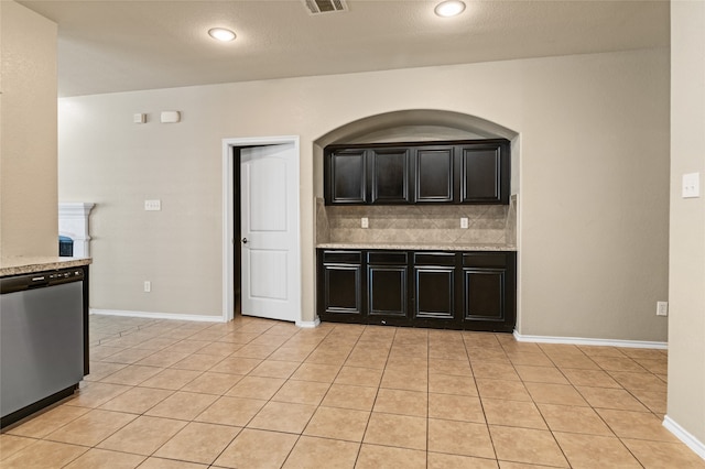 kitchen featuring tasteful backsplash, dishwasher, light stone countertops, and light tile patterned floors