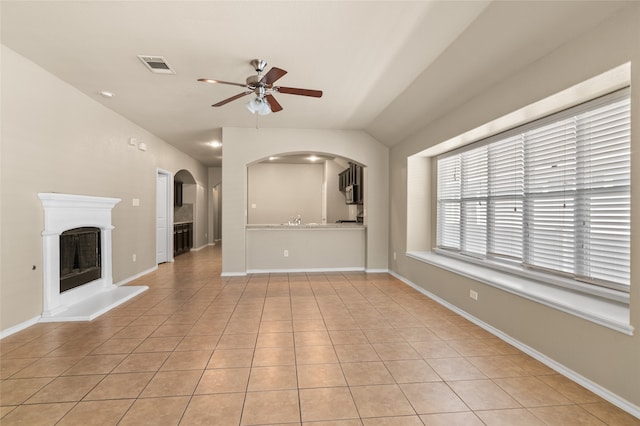 unfurnished living room featuring lofted ceiling, light tile patterned floors, sink, and ceiling fan