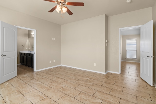 unfurnished bedroom with light tile patterned floors, ensuite bath, sink, and ceiling fan