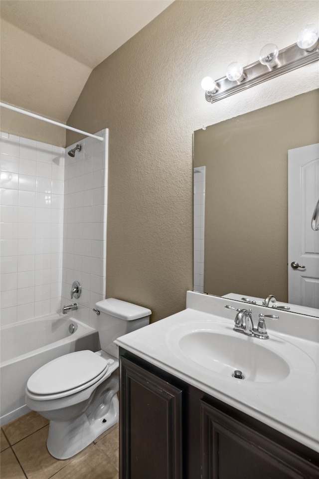 full bathroom featuring lofted ceiling, tile patterned flooring, vanity, tiled shower / bath, and toilet