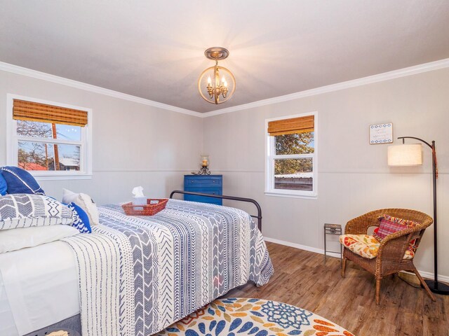 bedroom featuring hardwood / wood-style flooring, crown molding, an inviting chandelier, and multiple windows