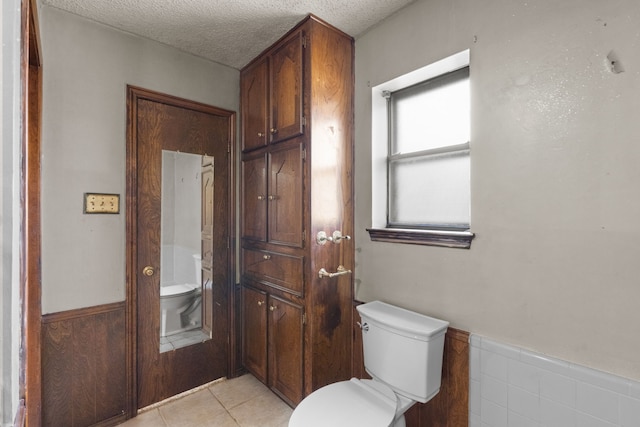 bathroom with tile patterned flooring, a textured ceiling, and toilet