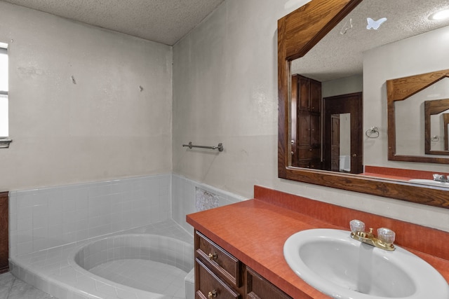 bathroom featuring vanity, tiled bath, and a textured ceiling