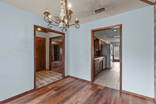 unfurnished dining area with a textured ceiling and light wood-type flooring