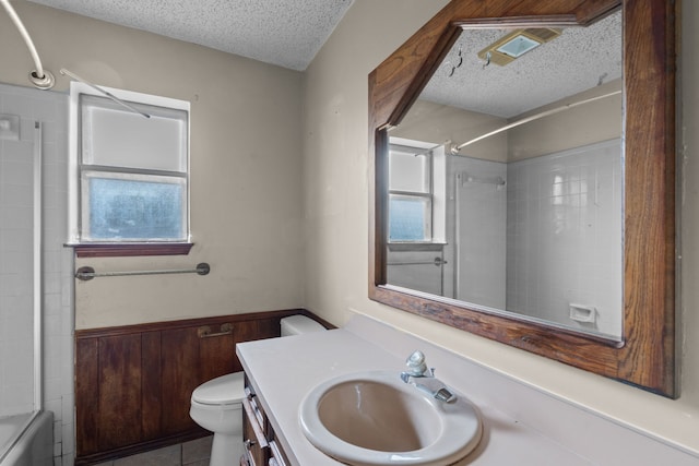 full bathroom with wooden walls, vanity, a textured ceiling, toilet, and tiled shower / bath