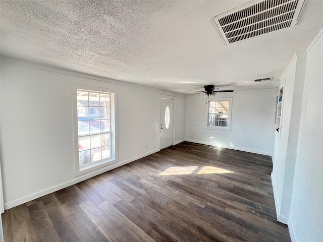 spare room with a ceiling fan, dark wood-type flooring, baseboards, and visible vents