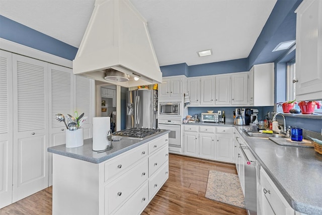 kitchen featuring stainless steel appliances, white cabinetry, and custom range hood