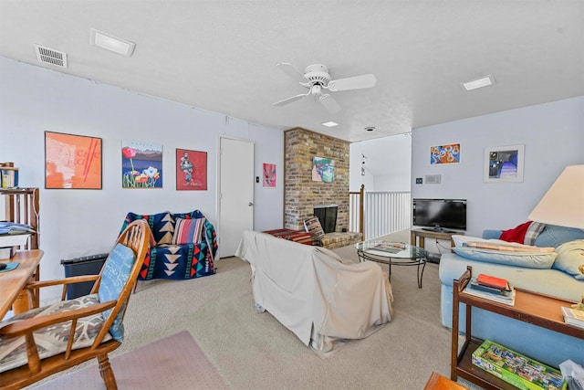 living room featuring ceiling fan, light colored carpet, a brick fireplace, and a textured ceiling