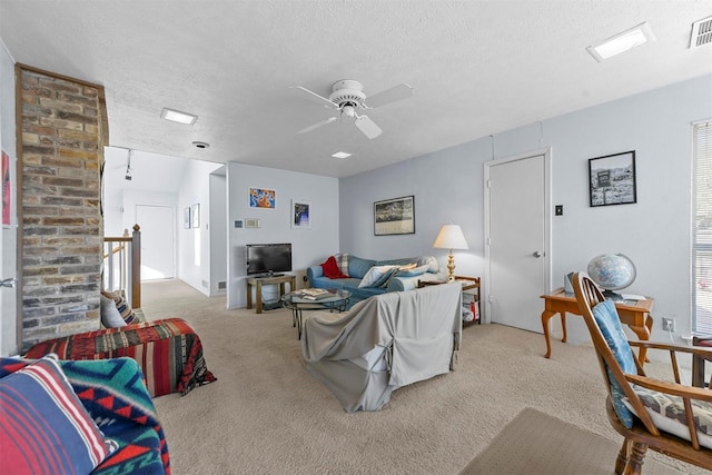 living room with ceiling fan, light colored carpet, and a textured ceiling