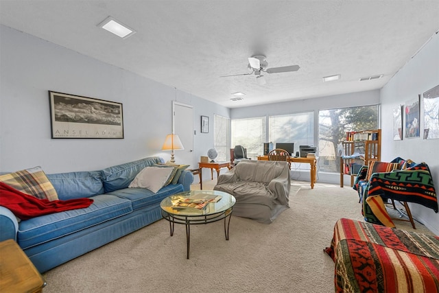 carpeted living room with ceiling fan and a textured ceiling