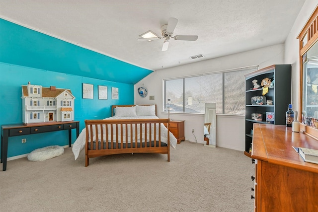 carpeted bedroom featuring ceiling fan, vaulted ceiling, and a textured ceiling