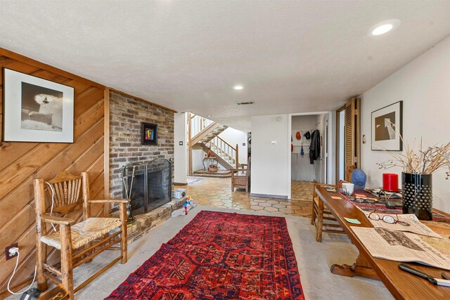 living room with a brick fireplace, wooden walls, and a textured ceiling