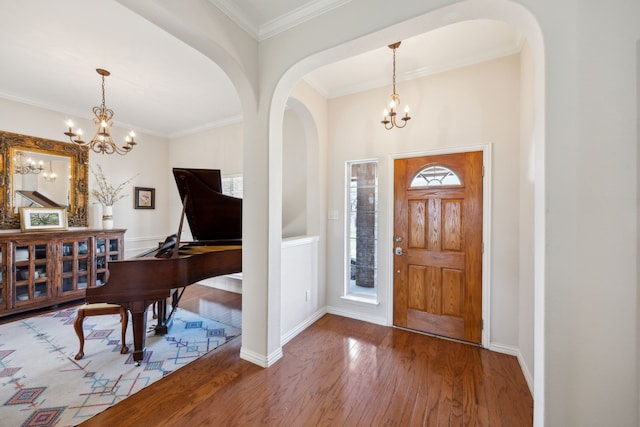 foyer featuring crown molding, a notable chandelier, hardwood / wood-style flooring, and plenty of natural light