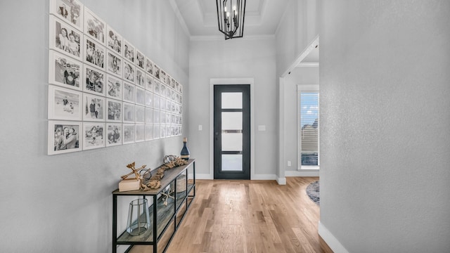 entryway featuring a high ceiling, crown molding, hardwood / wood-style floors, and a notable chandelier