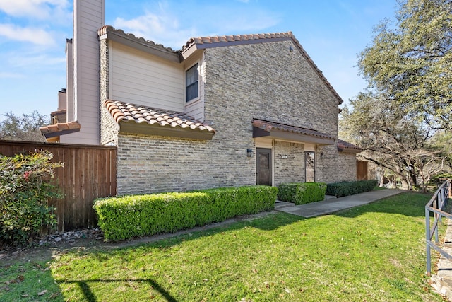 view of front of house with a chimney, fence, a tiled roof, and a front lawn