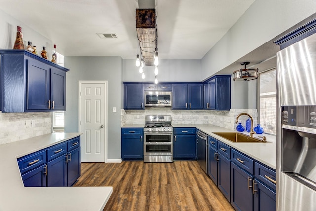 kitchen with appliances with stainless steel finishes, sink, dark wood-type flooring, and blue cabinetry