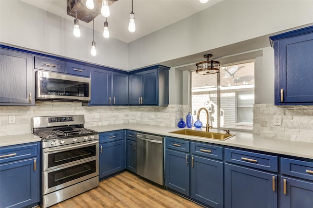 kitchen with sink, hanging light fixtures, stainless steel appliances, blue cabinets, and light wood-type flooring